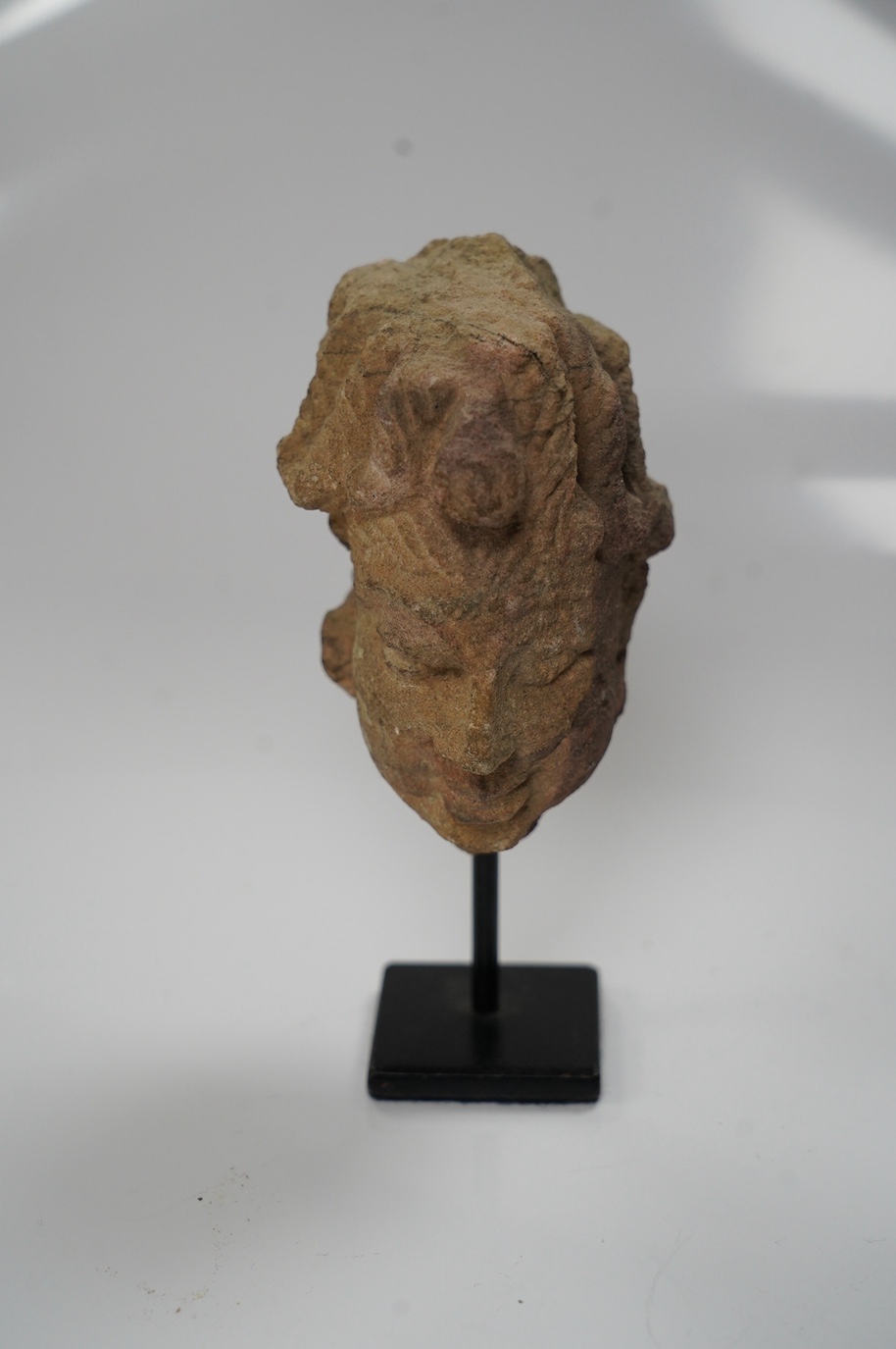 An Indian sandstone head of Shiva, 16th century, 8cm not including stand. Condition - good considering age